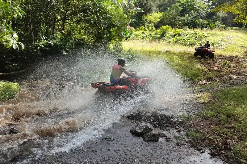 Riders on ATVs approaching a rustic rainforest hot spring near La Fortuna, Costa Rica