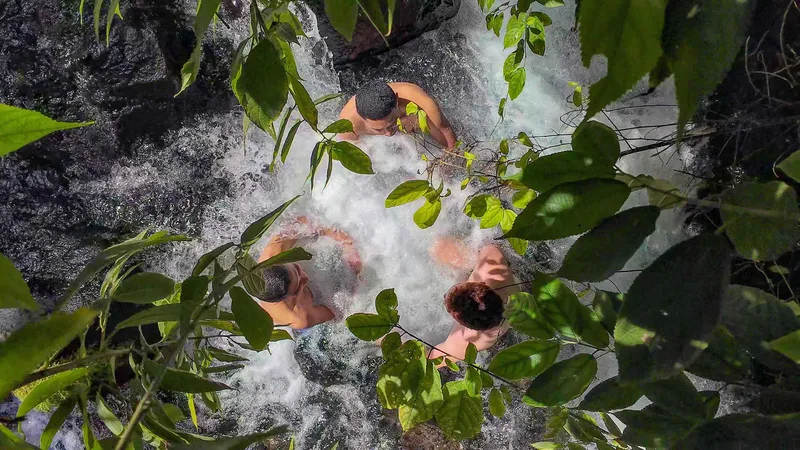Travelers wading through the natural hot springs river at Hot Springs Pura Vida near La Fortuna, Costa Rica